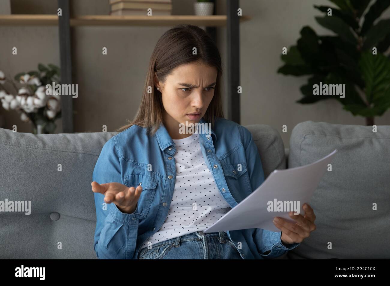 Unglückliche junge Frau, die sich beim Lesen von Nachrichten ängstlich fühlt. Stockfoto