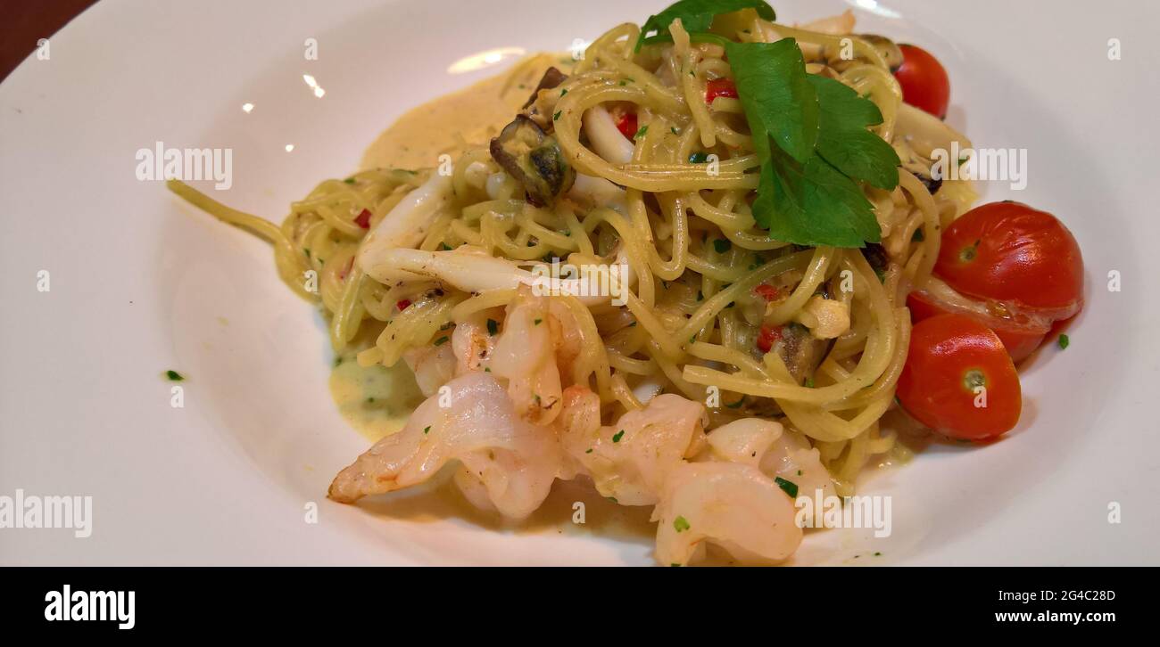 Spaghetti mit Garnelen, Tintenfisch, Tomaten, Knoblauch, Chili, Muscheln, Rahm und Petersilie. Stockfoto