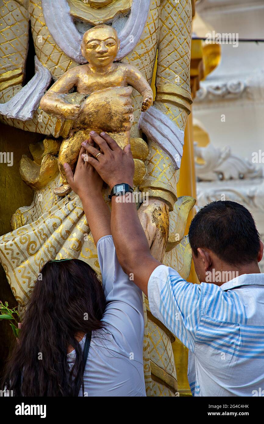 Ehepaar, das Buddha betet, um ein Kind in der Shwedagon-Pagode in Yangon, Myanmar, zu haben Stockfoto