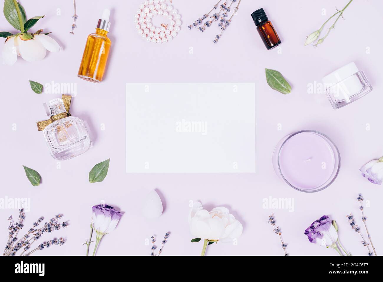 Festliche Komposition blank weißes Blatt Papier auf violettem Hintergrund zwischen femininen Accessoires und Kosmetika, flach liegend. Stockfoto