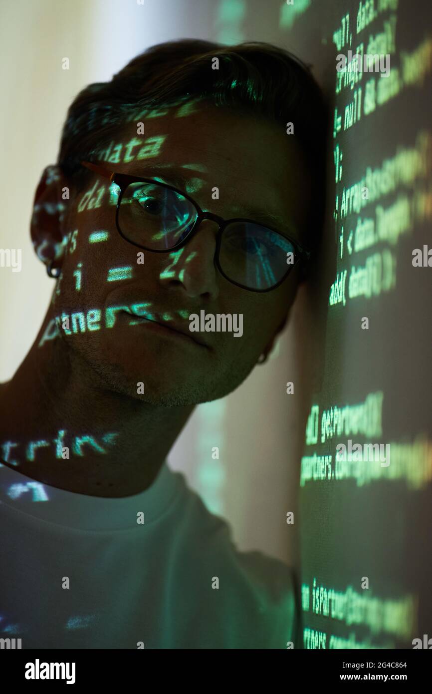 Porträt eines IT-Managers in einer Brille, der in der Nähe des Whiteboard mit Computercode auf die Kamera schaut Stockfoto
