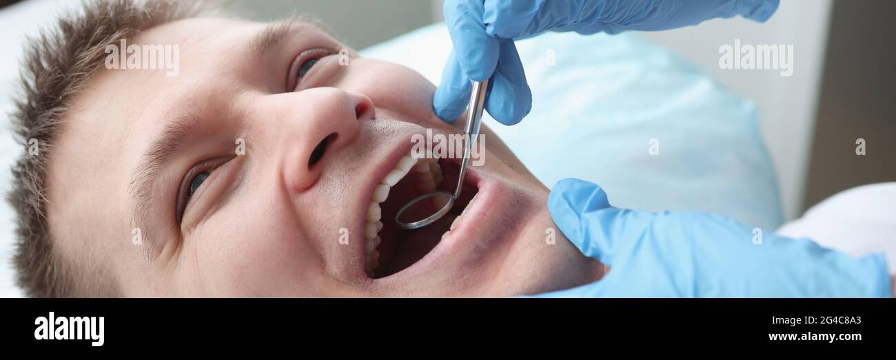 Zahnarzt, der Mundhöhle des männlichen Patienten mit Spiegel untersucht Stockfoto Zahnarzt, der Mundhöhle des männlichen Patienten mit Spiegel untersucht Stockfoto