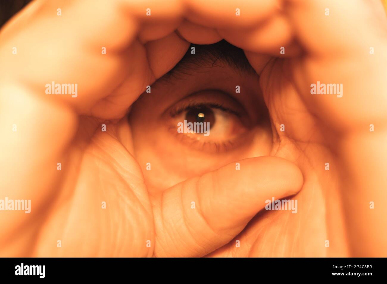 Detail der Hände, die sie als Teleskop verwenden, um sie als Pirat zu beobachten und das Auge einer Person mit selektivem Fokus im Blick zu lassen Stockfoto