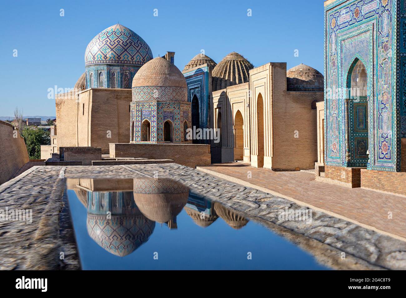 Mausoleen und Kuppeln des historischen Friedhofs von Shahi Zinda und ihre Reflexionen in Pfützen, Samarkand, Usbekistan. Stockfoto