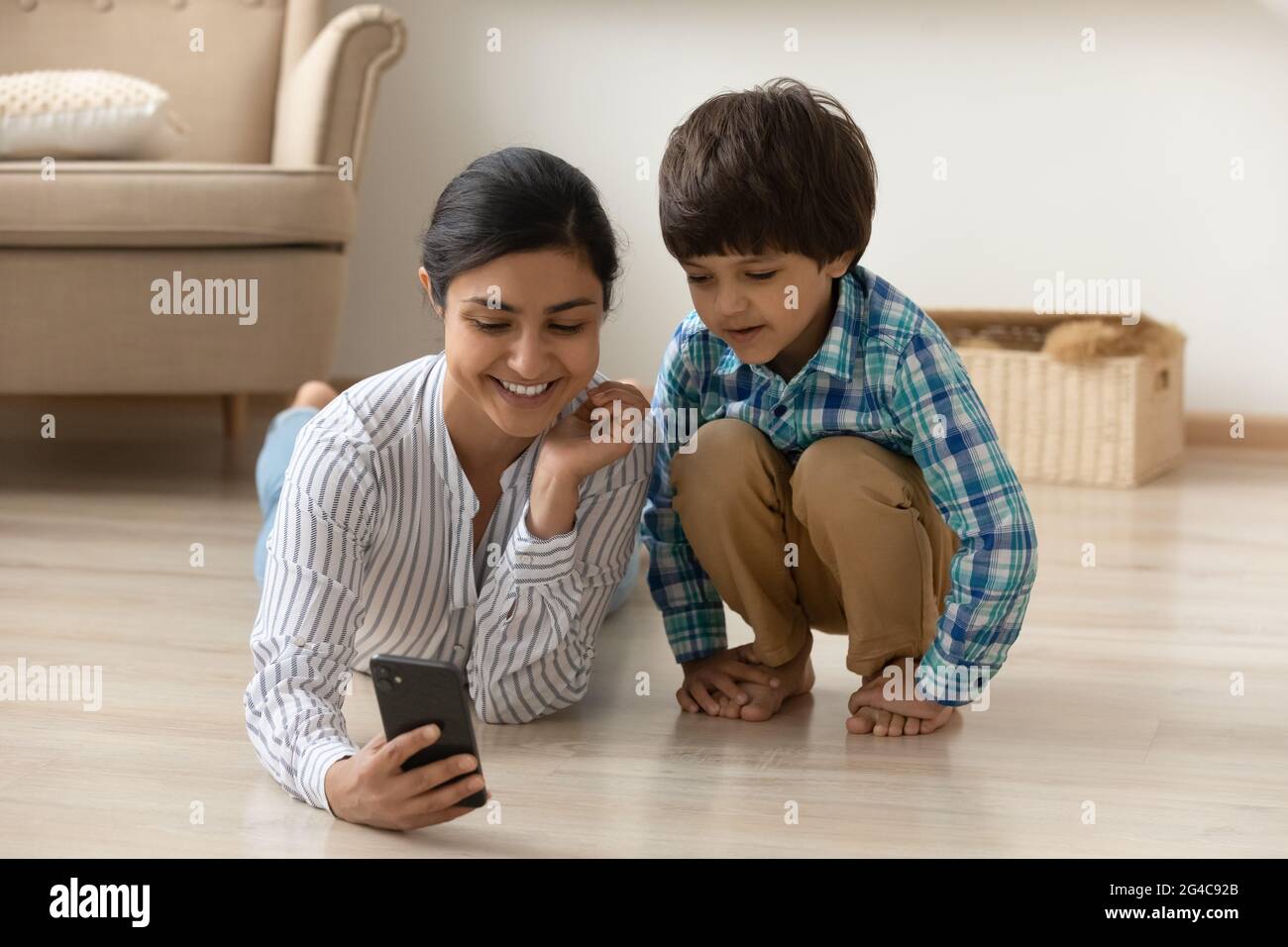 Lächelnde indische Mutter und kleiner Sohn benutzen Handy Stockfoto