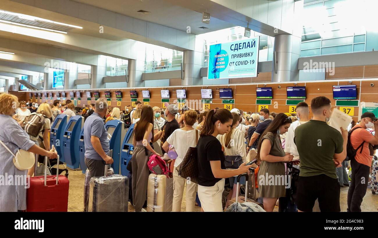 Moskau, Russland, Flughafen Sheremetyevo, Menschen mit Gepäck Menge im Check-in-Bereich. Blaues Banner (auf Russisch) Appell: "Gegen COVID-19 impfen" Stockfoto