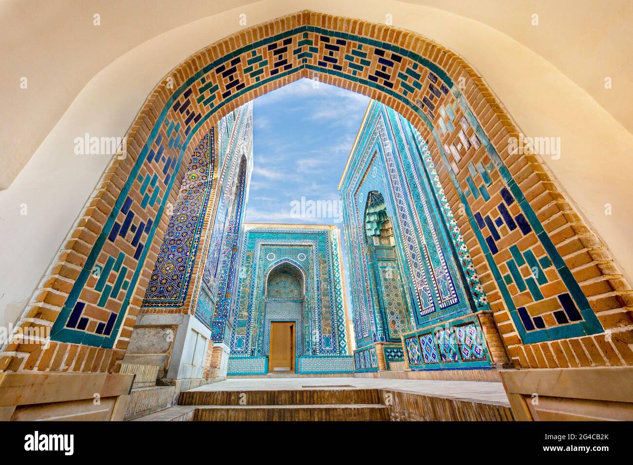 Historischer Friedhof von Shahi Zinda mit seinen fein dekorierten Mausoleen durch einen Bogen in Samarkand, Usbekistan. Stockfoto