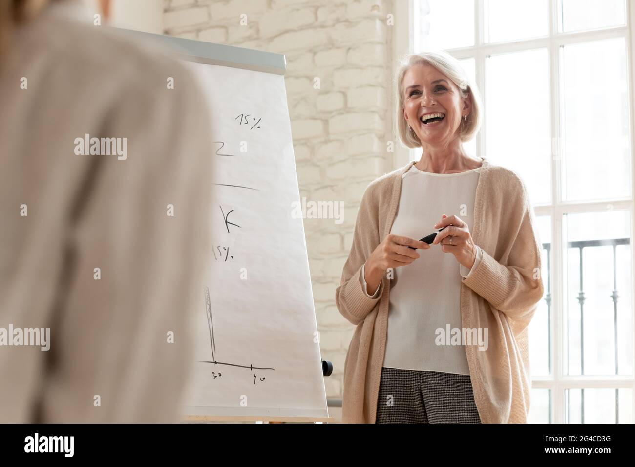 Eine aufgeregte Geschäftsfrau mittleren Alters, die eine Flipchart-Präsentation vorstellte Stockfoto