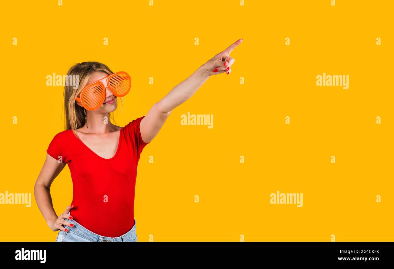 Glückliche Frau in einer großen Brille, die mit dem Finger auf den Kopierraum zeigt. Werbung. Saisonangebot. Rabatt. Stockfoto