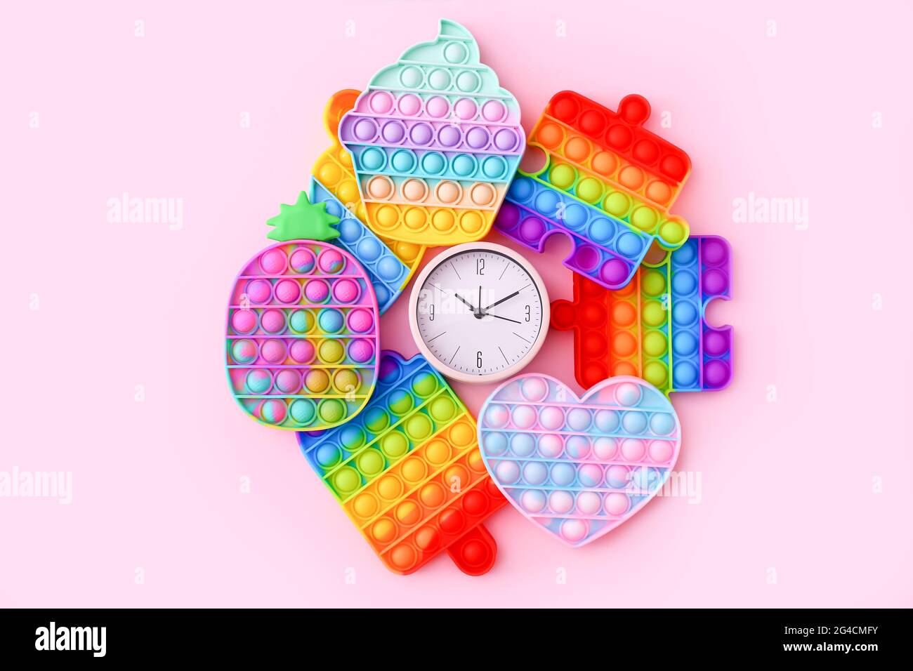 Farbenfrohe Antistress-Sinnesspielzeug mit Uhr auf rosa Hintergrund Stockfoto