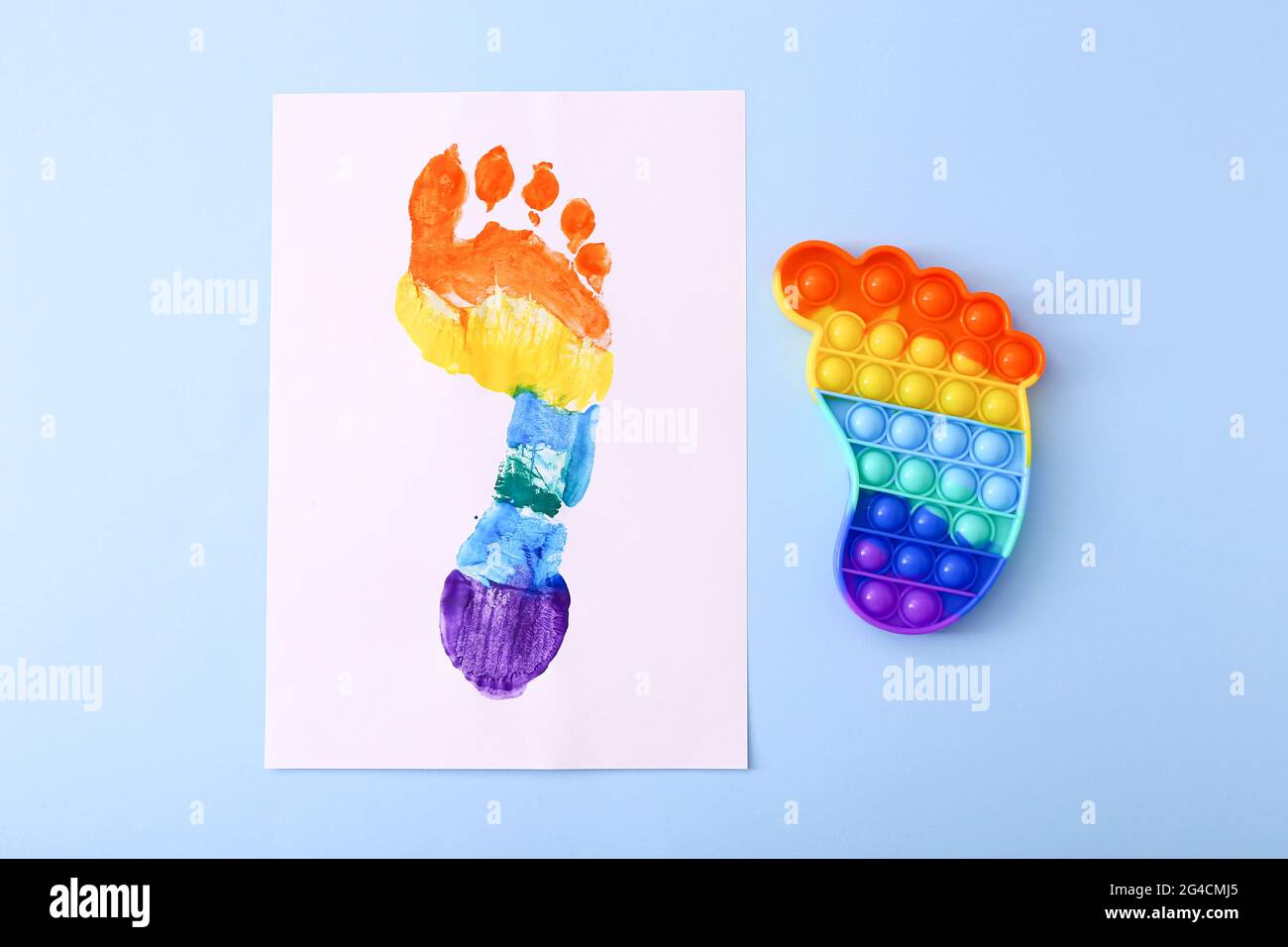 Neue trendige beliebte Silikon bunte Anti Stress Pop IT Spielzeug für Kinder und bunte Fußabdruck auf blauem Hintergrund. Stockfoto