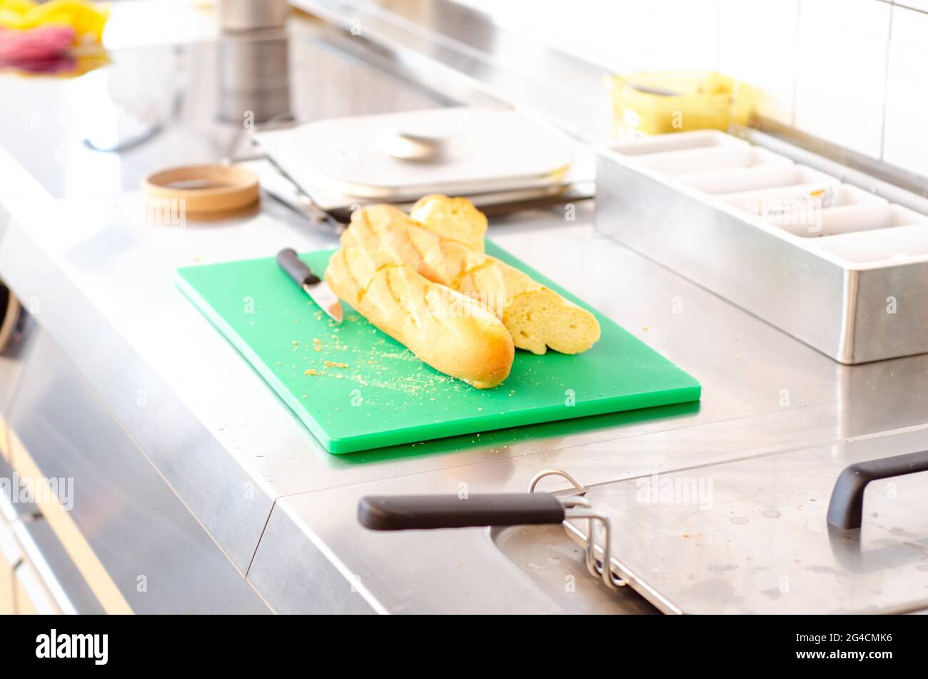 Ein Blick auf geschnittenes französisches Baguette auf einem grünen Edelstahlbrett auf einem Küchentisch Stockfoto