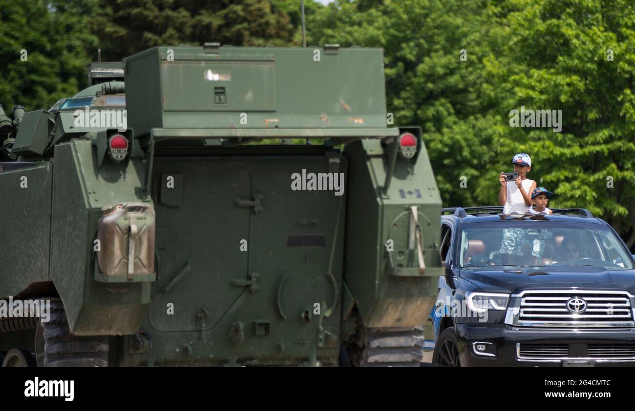 Milton, Kanada. Juni 2021. Ein Kind fotografiert am 20. Juni 2021 ein Militärfahrzeug beim 2021 Mega Wheels Drive-Thru Event in Milton, Ontario, Kanada. Die Drive-Thru-Veranstaltung, die vom 18. Bis 27. Juni stattfindet, bietet Monster-Trucks, Oldtimer, Militärfahrzeuge und mehr auf einer 2.5 km langen Strecke. Quelle: Zou Zheng/Xinhua/Alamy Live News Stockfoto