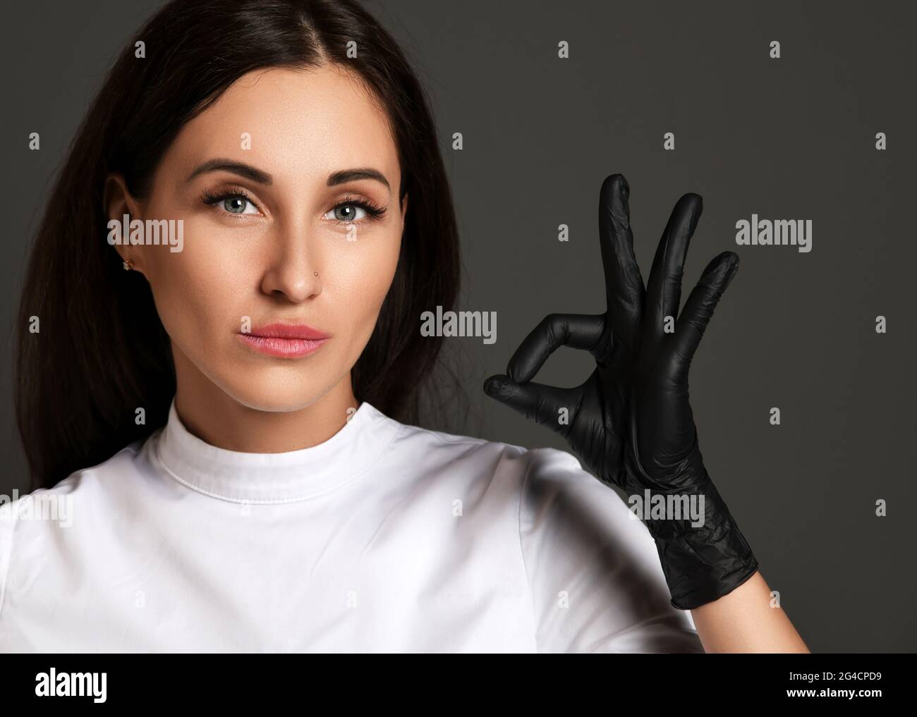 Porträt einer attraktiven jungen Frau Arzt Zahnarzt in weißer Uniform und Latexhandschuhe zeigt ok gutes Zeichen Stockfoto