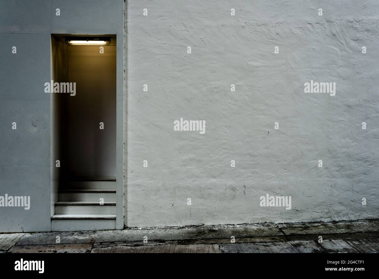 Ein schattiges Tor mit Stufen und einer strukturierten weißen Wand, Wan Chai, Hong Kong Island Stockfoto