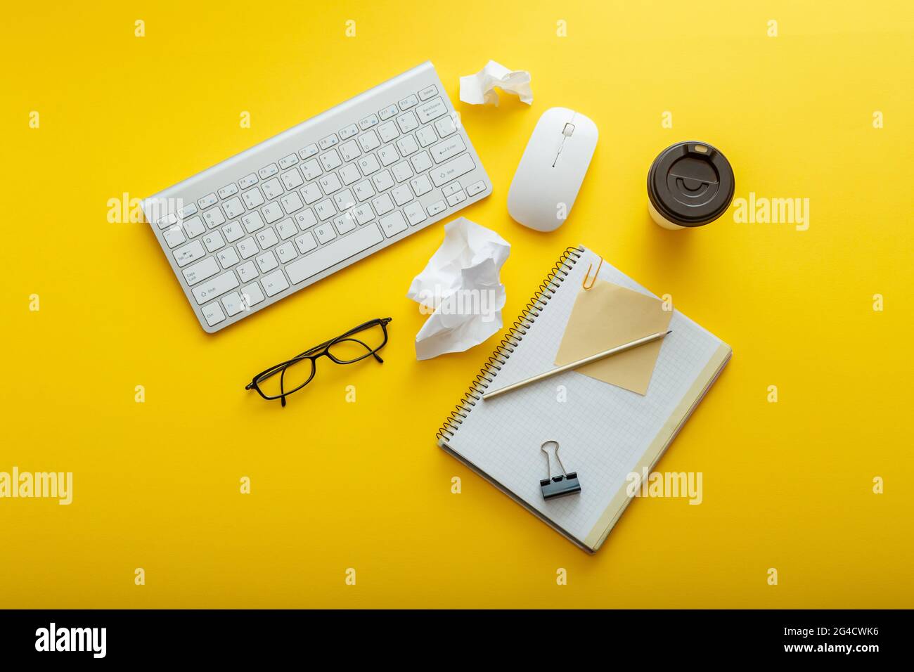 Arbeitsbereich, Tischanordnung mit Notiztastatur, Kaffeetassen, Gläser mit hellem gelben Hintergrund. Moderner Schreibtisch, Arbeitsbereich mit flacher Lay-Komposition. Weiß Stockfoto