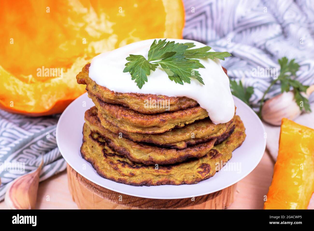 Traditionelle hausgemachte vegetarische Kürbiskartoffel-Pfannkuchen mit saurer Creme auf hellem Hintergrund. Stockfoto