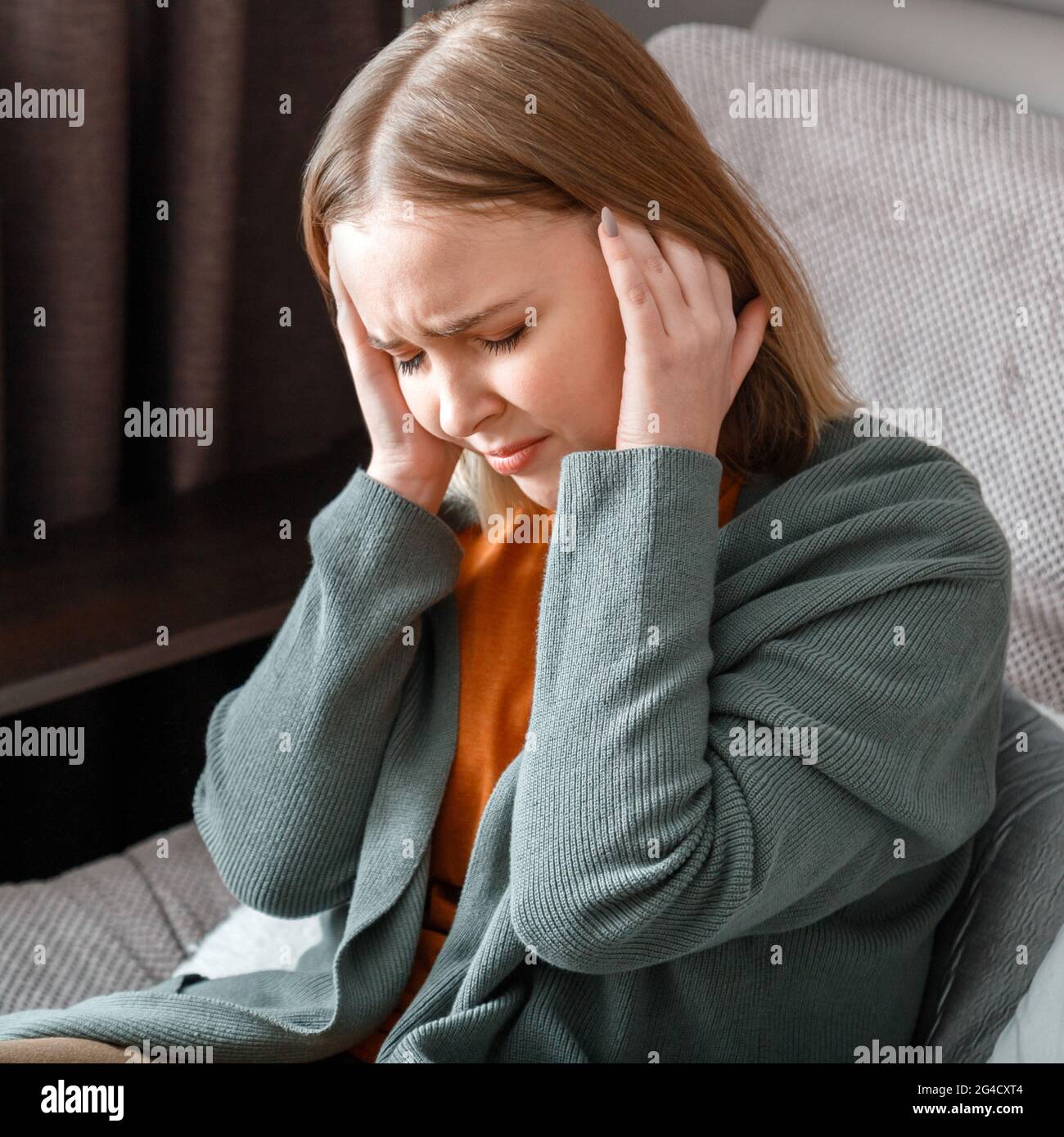 Verstörte Frau mit schweren Migränekopfschmerzen hält Schläfen mit den  Händen. Frau hat Fieber und Kopfschmerzen, die allein zu Hause auf dem Sofa  sitzen. Platz in der Nähe Stockfotografie - Alamy