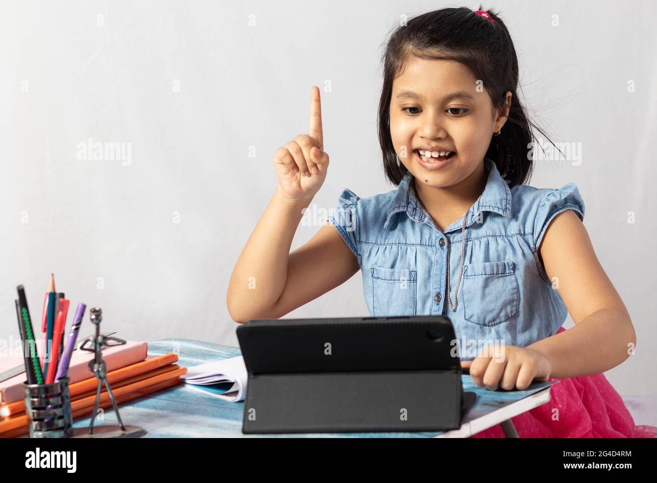 Ein hübsches indisches Mädchen, das am Online-Kurs mit Tablet auf weißem Hintergrund teilnimmt Stockfoto