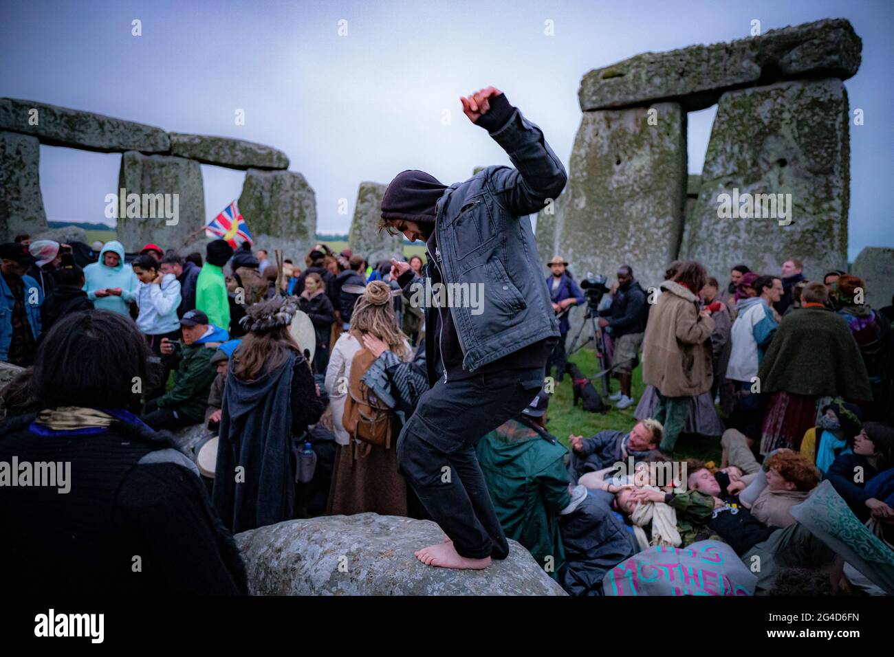 Menschen im Steinkreis während der Sommersonnenwende in Stonehenge, wo einige Menschen über den Zaun sprangen, um den Platz zu betreten und den Sonnenaufgang am längsten Tag in Großbritannien zu beobachten. Die Steine wurden für die Feierlichkeiten, bei denen große Menschenmengen im Kreis zu sehen sind, aufgrund der Coronavirus-Lockdown-Erweiterung offiziell geschlossen. Bilddatum: Montag, 21. Juni 2021. Stockfoto