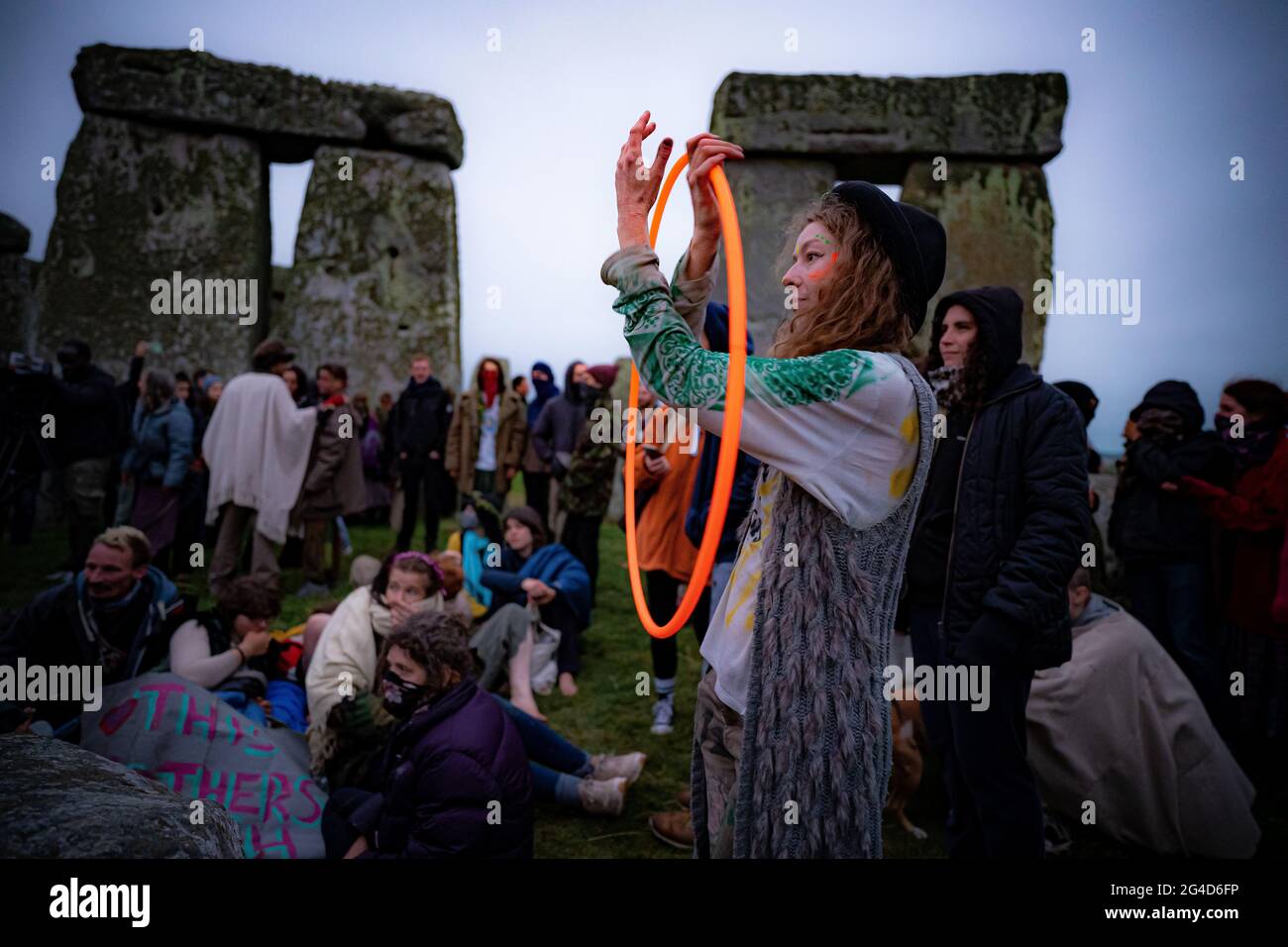 Menschen im Steinkreis während der Sommersonnenwende in Stonehenge, wo einige Menschen über den Zaun sprangen, um den Platz zu betreten und den Sonnenaufgang am längsten Tag in Großbritannien zu beobachten. Die Steine wurden für die Feierlichkeiten, bei denen große Menschenmengen im Kreis zu sehen sind, aufgrund der Coronavirus-Lockdown-Erweiterung offiziell geschlossen. Bilddatum: Montag, 21. Juni 2021. Stockfoto