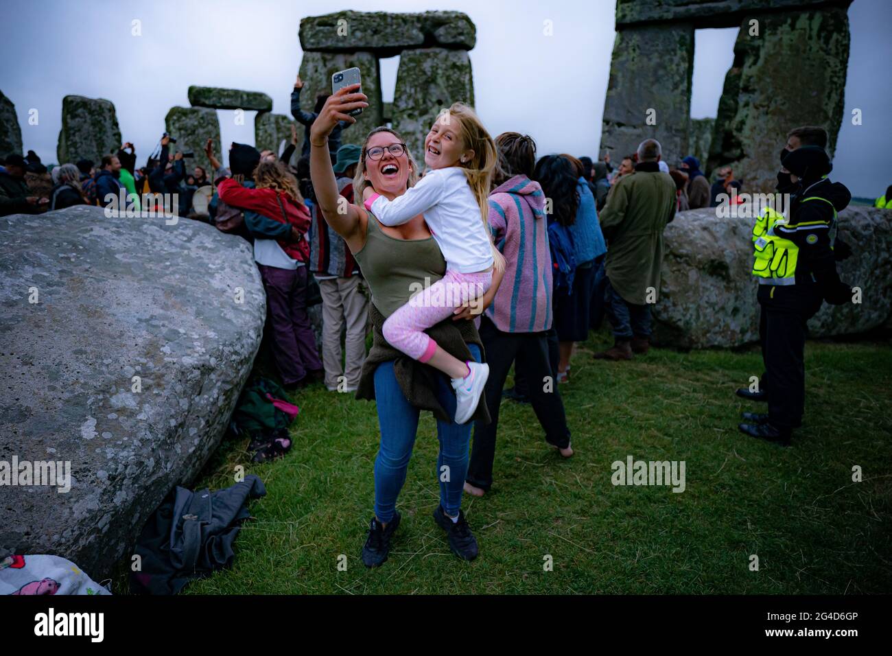 Während der Sommersonnenwende in Stonehenge machen Menschen Selfies im Steinkreis, wo einige Menschen über den Zaun sprangen, um den Sonnenaufgang am längsten Tag in Großbritannien zu beobachten. Die Steine wurden für die Feierlichkeiten, bei denen große Menschenmengen im Kreis zu sehen sind, aufgrund der Coronavirus-Lockdown-Erweiterung offiziell geschlossen. Bilddatum: Montag, 21. Juni 2021. Stockfoto