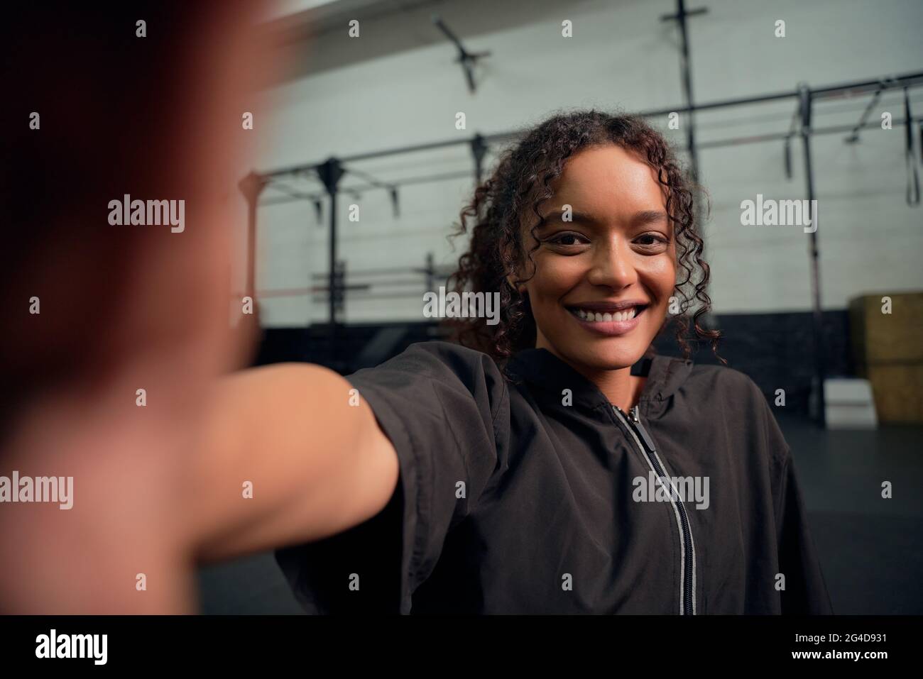 Glückliche afroamerikanische Frau, die im Fitnessstudio ein Selfie macht. Fröhliche Mischling Frau lächelt an der Kamera. Hochwertige Fotos Stockfoto