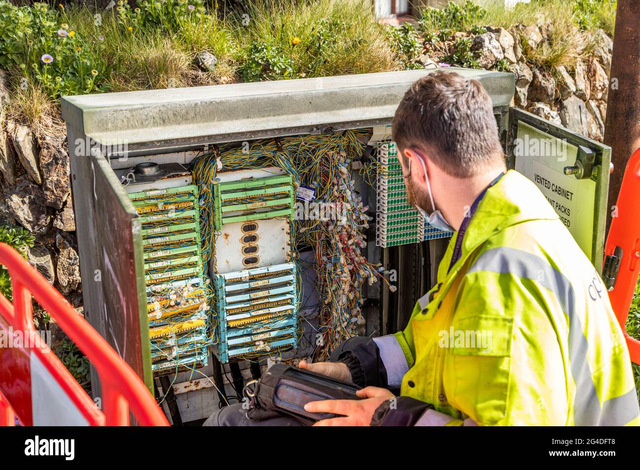 Ein Telekommunikationsingenieur arbeitet an der Lösung von Verbindungsproblemen in einem Straßenkabinett in Cornwall, England Stockfoto