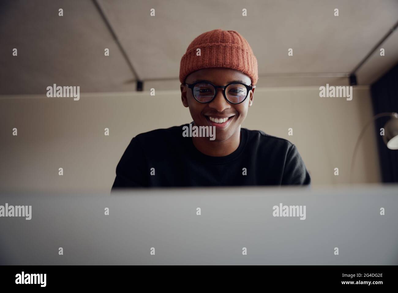 Afroamerikanischer Mann, der von zu Hause aus mit einem Laptop arbeitet. Glücklicher afroamerikanischer Mann, der von zu Hause aus mit Kopfhörern arbeitet. Hochwertige Fotos Stockfoto