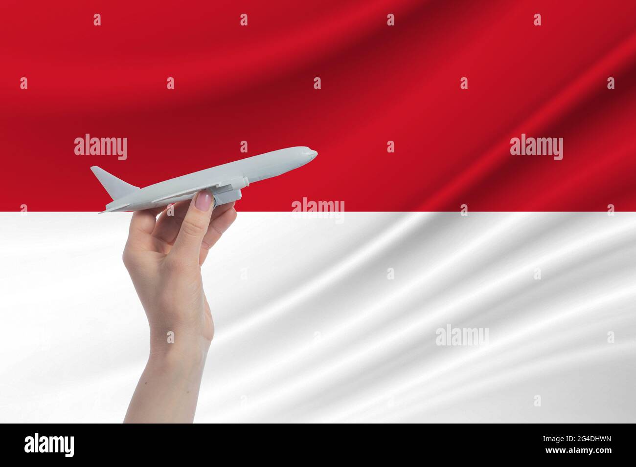 Flugzeug in der Hand mit der Nationalflagge Indonesiens Reise nach Indonesien. Stockfoto