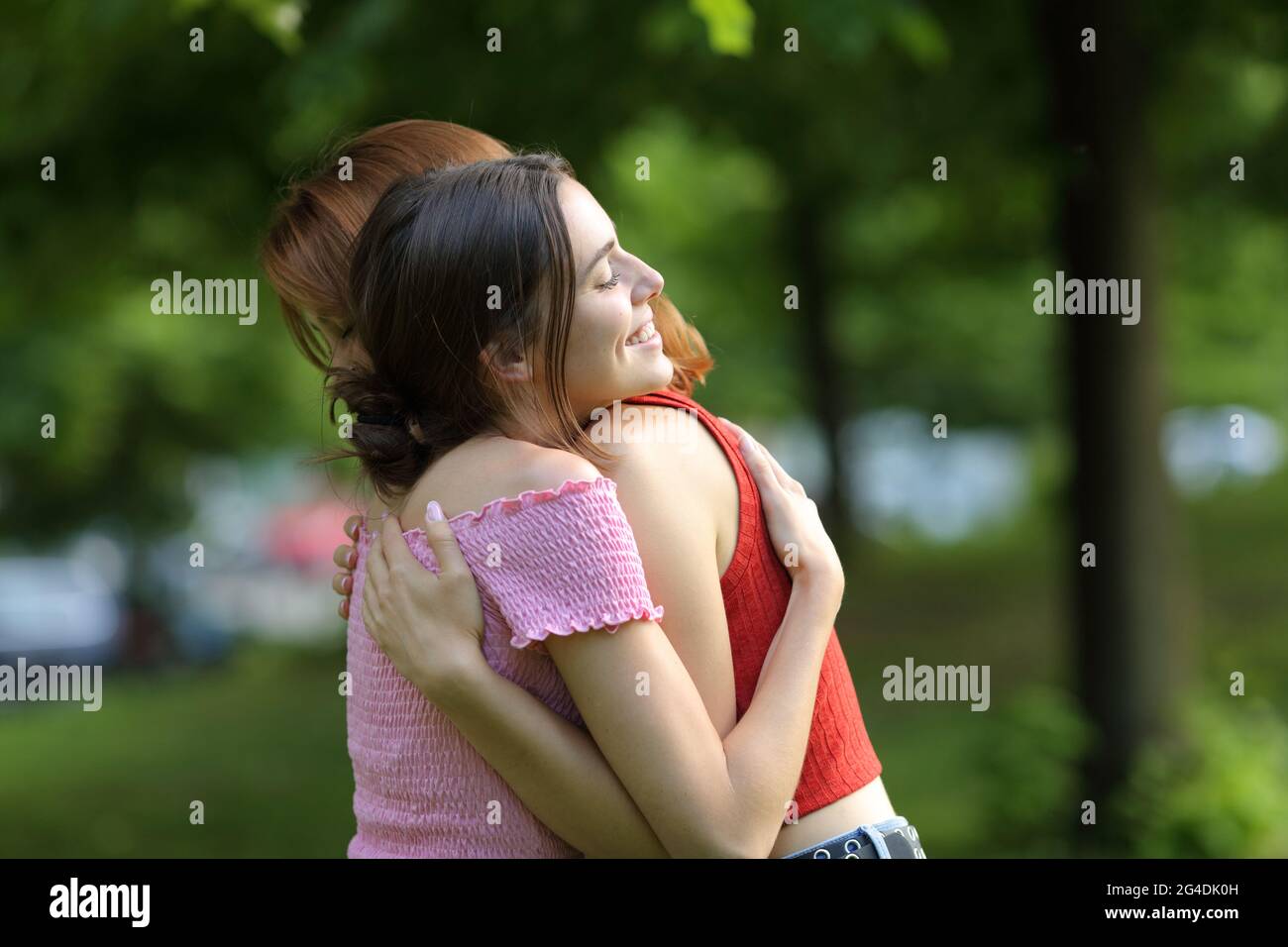 Zwei glückliche Frauen umarmen sich und treffen sich in einem grünen Park Stockfoto