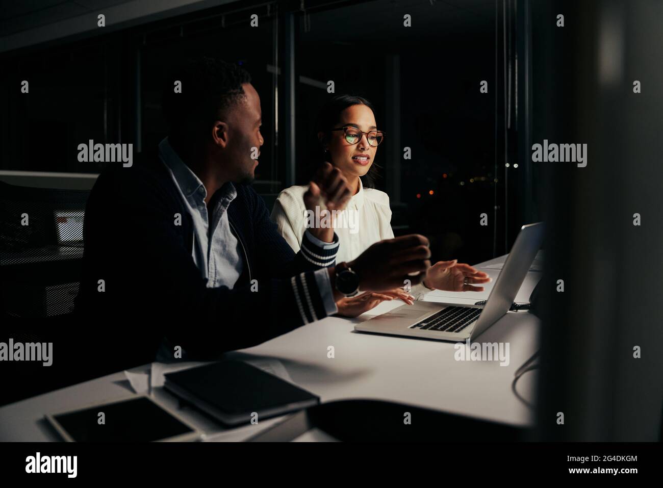 Multiethnische Geschäftsleute diskutieren das Projekt spät in der Nacht auf einem Laptop in einem neuen modernen Büro Stockfoto