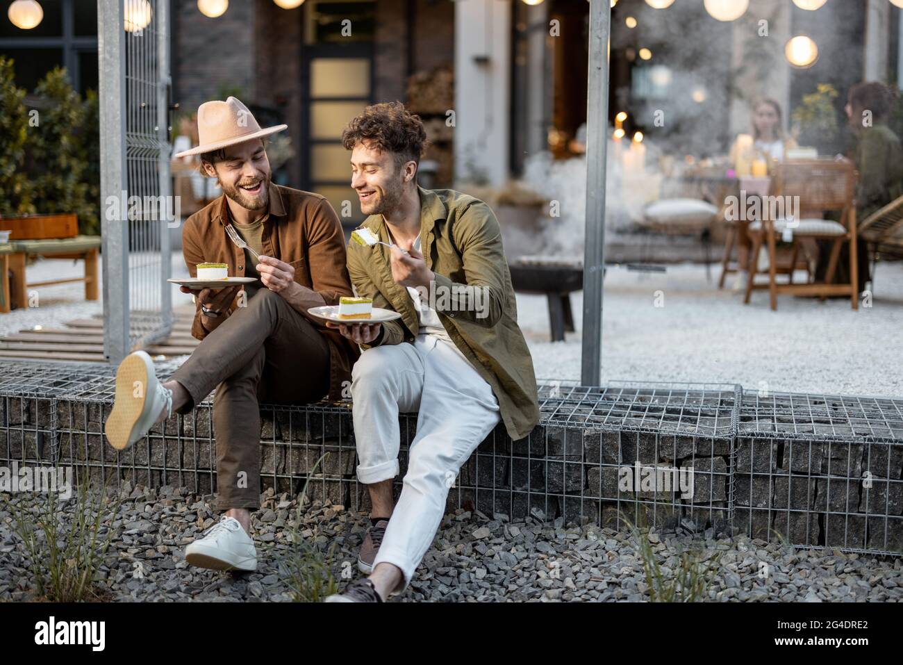 Zwei männliche Freunde sprechen auf einer Veranda des Landhauses Stockfoto
