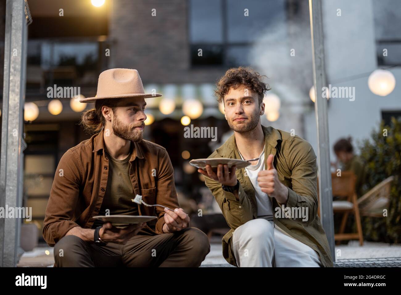 Zwei männliche Freunde sprechen auf einer Veranda des Landhauses Stockfoto