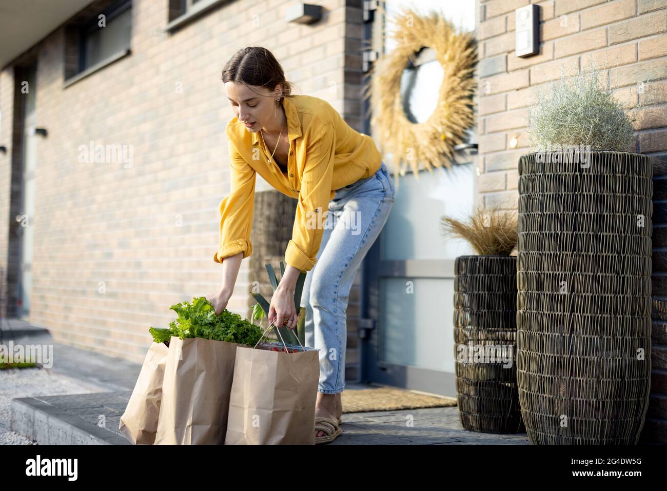 Hausfrau, die online auf der Veranda ihres Hauses gekaufte Lebensmittel erhält Stockfoto