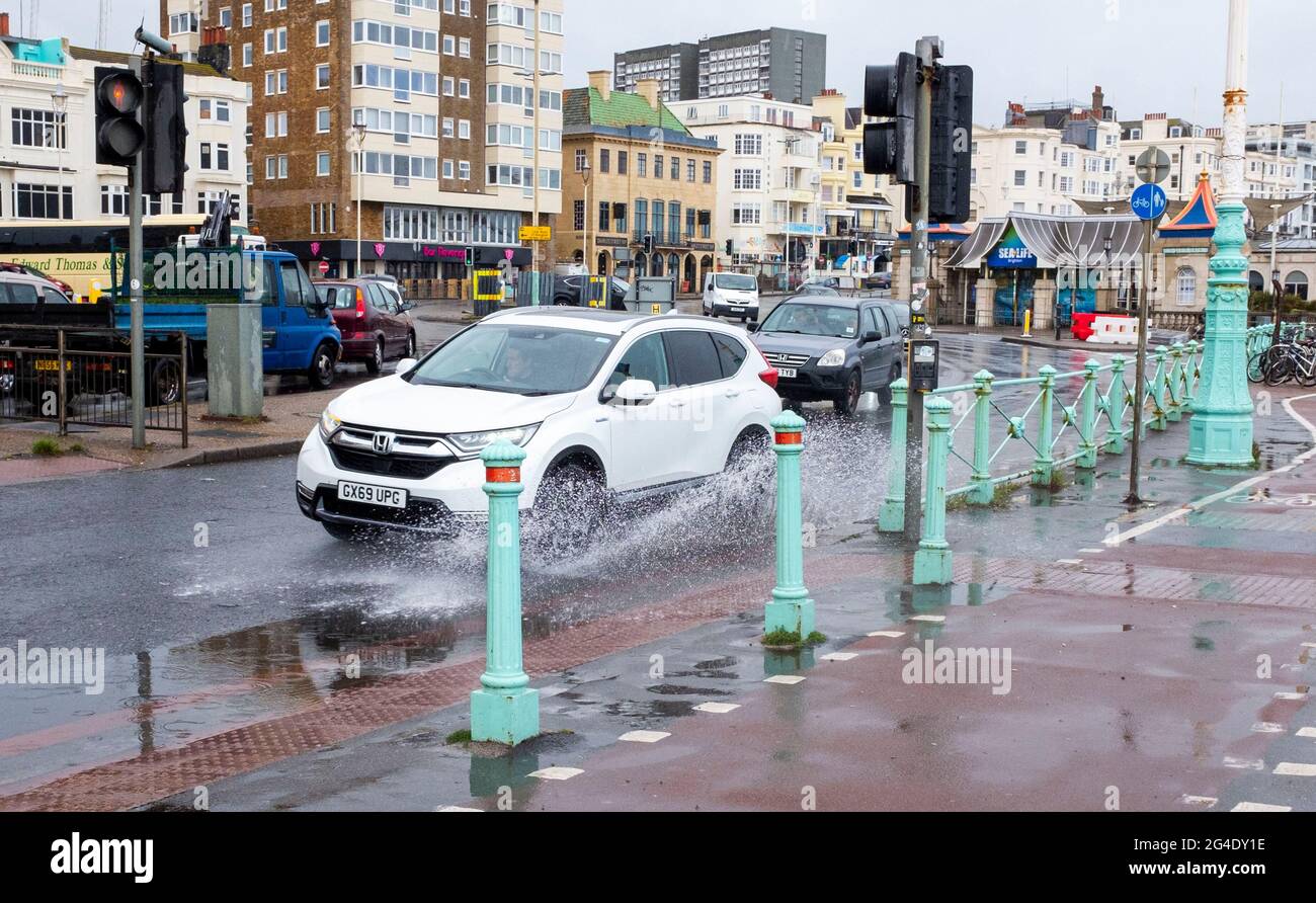 Brighton UK 21. Juni 2021 - der Verkehr spritzt durch Pfützen, während heute starker Regen die Sommersonnenwende an der Strandpromenade von Brighton dämpft : Credit Simon Dack / Alamy Live News Stockfoto