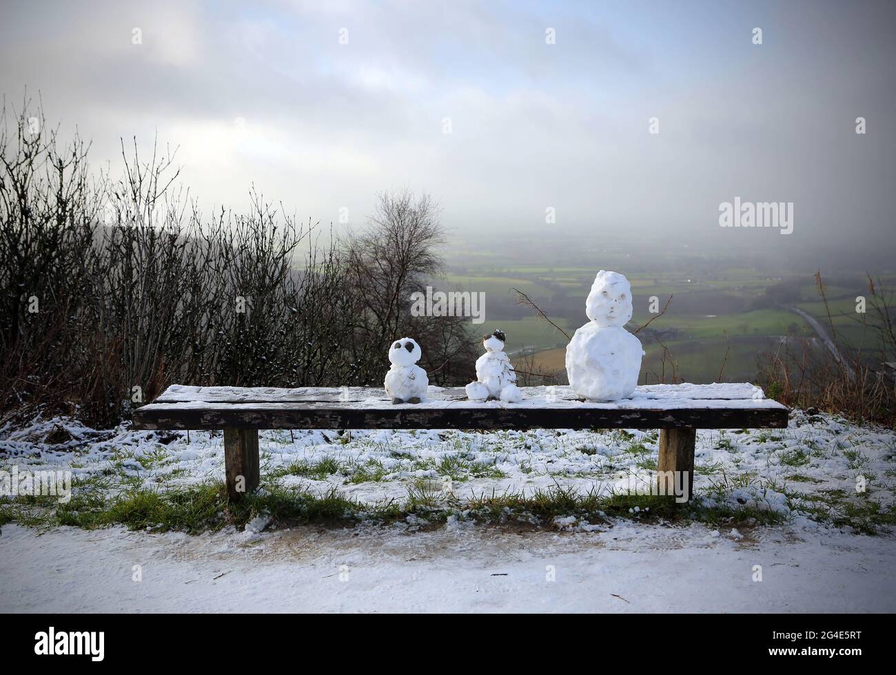 Drei Schneemänner sitzen am Heiligabend auf einer Bank auf der schneebedeckten Spitze der Sutton Bank im North York Moors National Park in North Yorkshire. Stockfoto