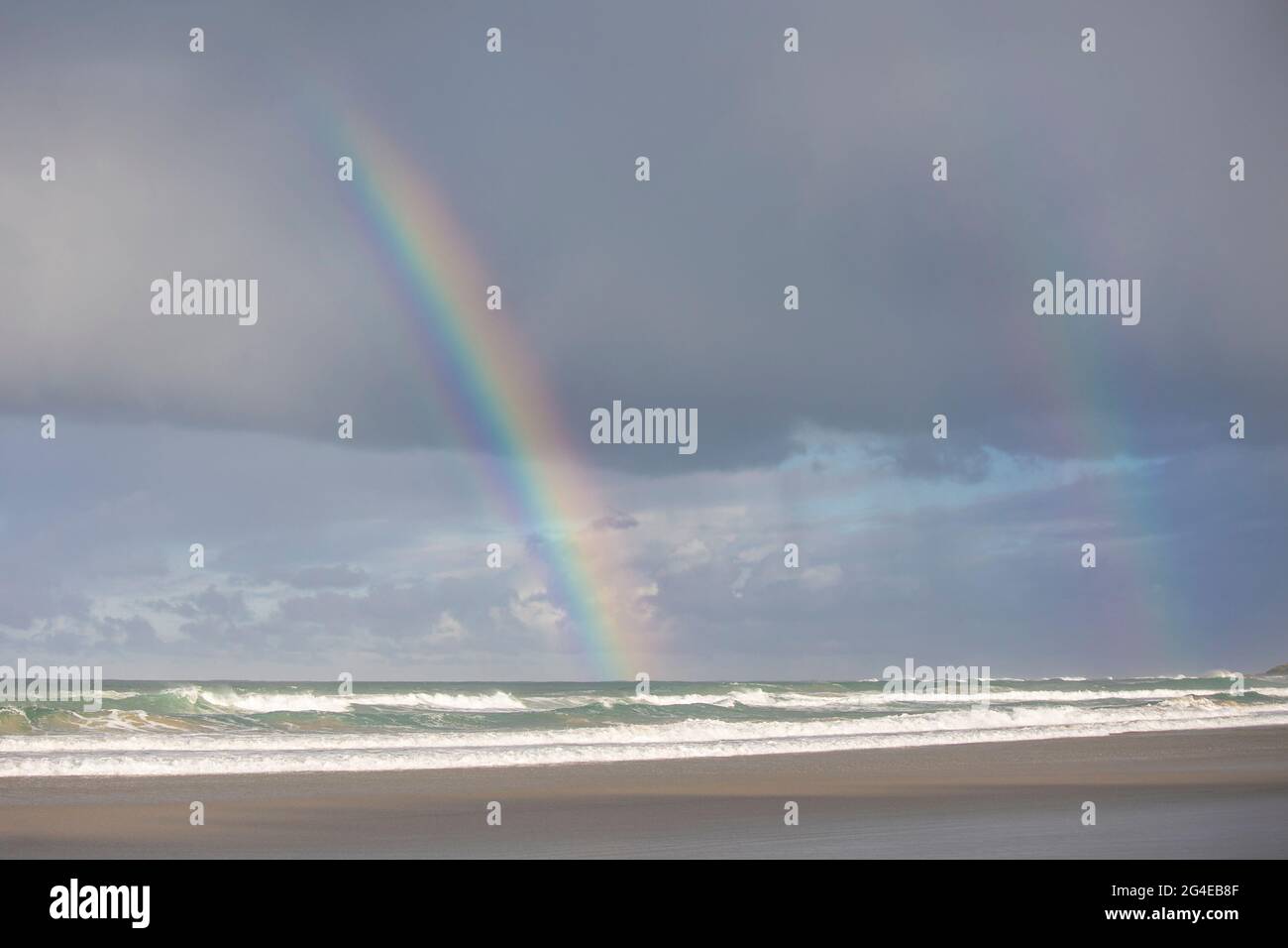 Ein heller und klarer Regenbogen in einem wolkigen Himmel über dem Meer Stockfoto