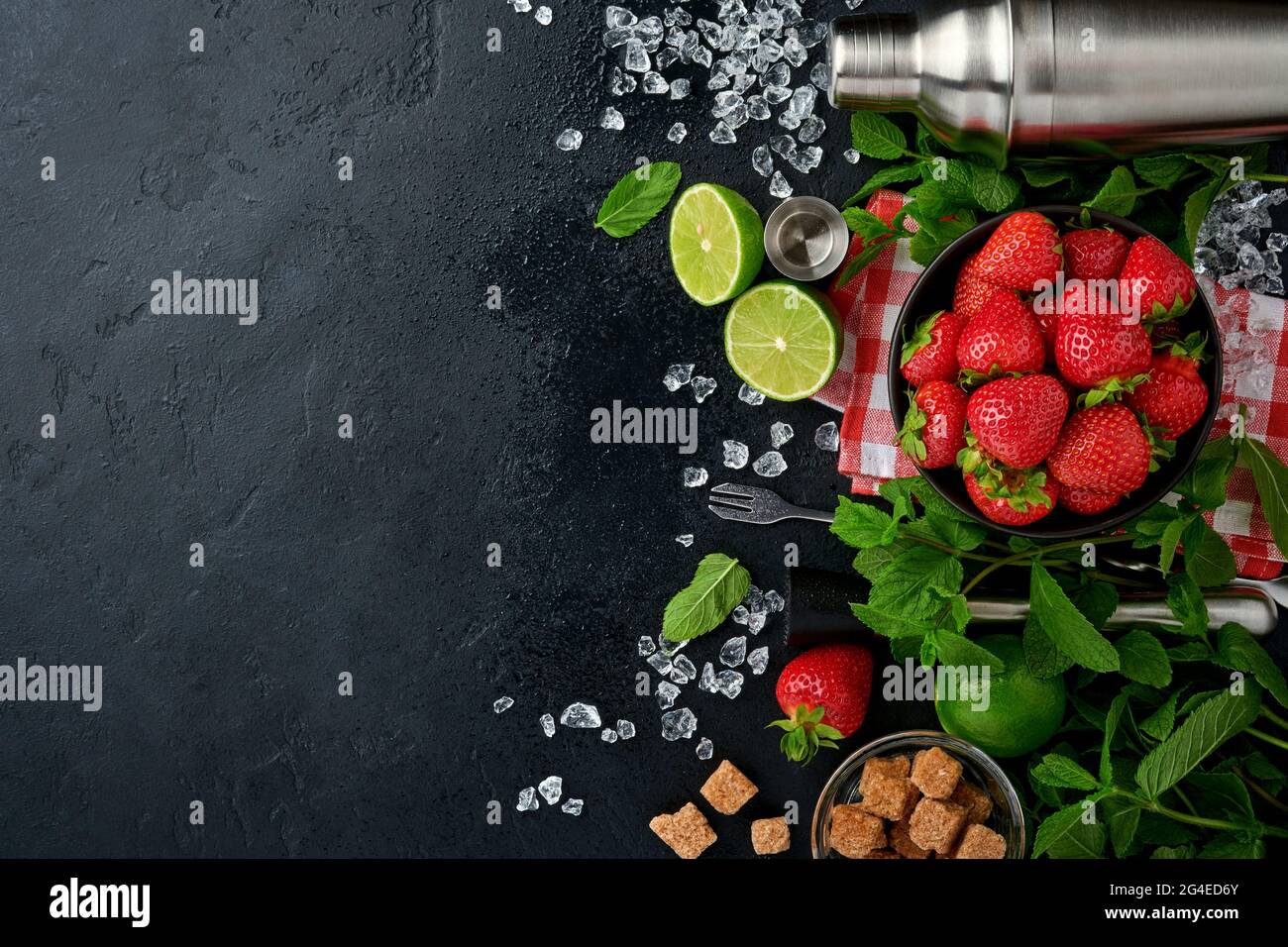 Lebensmittel Frische Zutaten für die Herstellung von Limonade, infundiert entgiftendes Wasser oder Cocktail. Erdbeeren, Limette, Minze, Basilikum, Rohrzucker, Eiswürfel und Shaker auf Blac Stockfoto