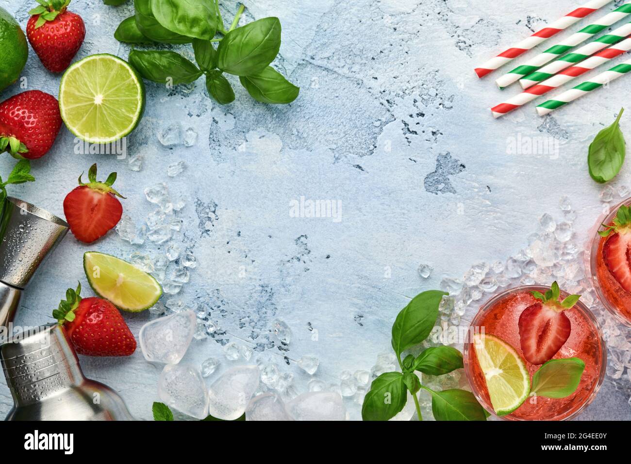 Zwei Gläser Punsch und frische Zutaten für die Herstellung von Limonade, infusem Detox-Wasser oder Cocktail. Erdbeeren, Limette, Minze, Basilikum, Eiswürfel und Shaker Stockfoto