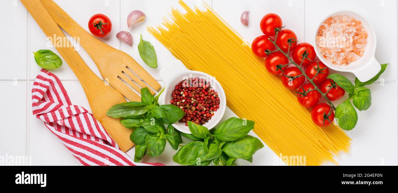 Spaghetti, frische Tomaten, Kräuter und Gewürze. Zusammensetzung von gesunden Zutaten isoliert auf weißem Hintergrund, Draufsicht. Modell. Stockfoto