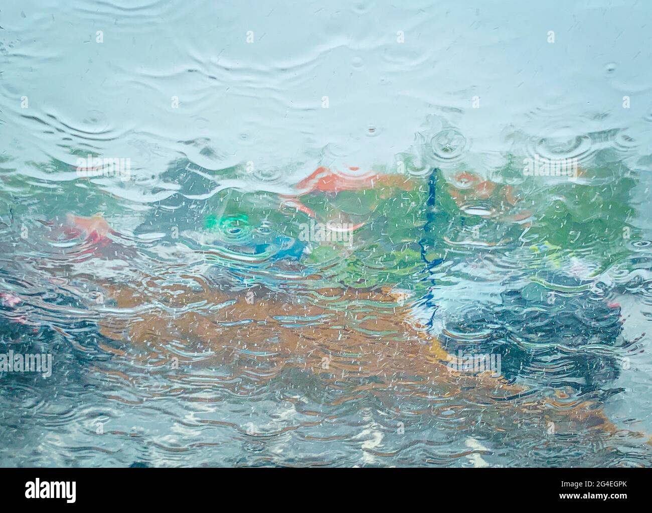 Abstraktes Bild eines sintflutartigen Regens, der an einem Sommermorgen im Juni in Essex, Großbritannien, auf die Windschutzscheibe fällt Stockfoto