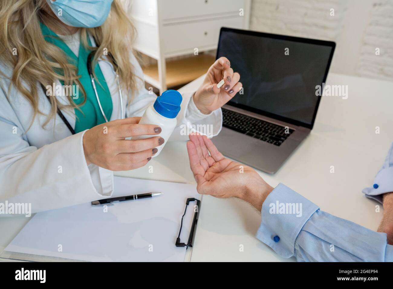 Junge attraktive kaukasische Ärztin, die ein Glas mit Pillen hält, die weibliche Patientin über Verschreibung und medizinische Behandlung informieren. Gesundheit, Medizin Stockfoto