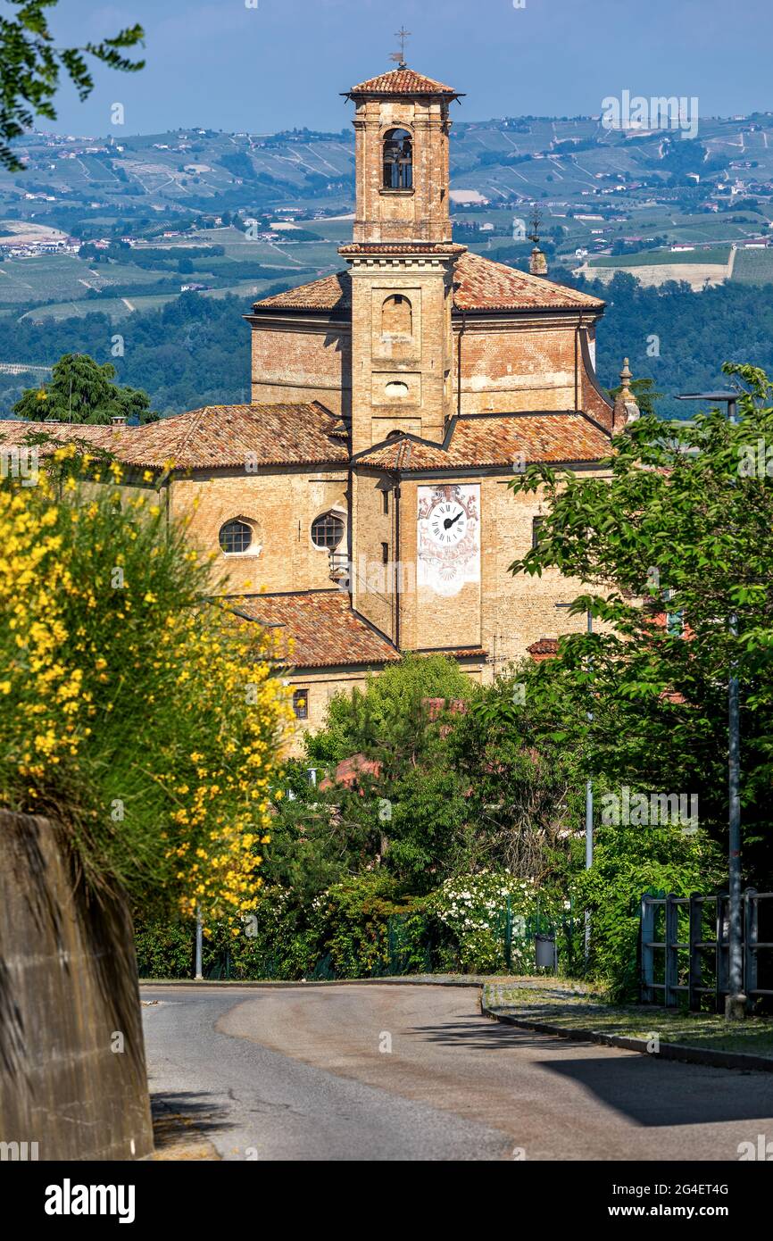 Blick auf die schmale Straße und die alte Backsteinkirche in der Kleinstadt Guarene im Piemont, Norditalien. Stockfoto