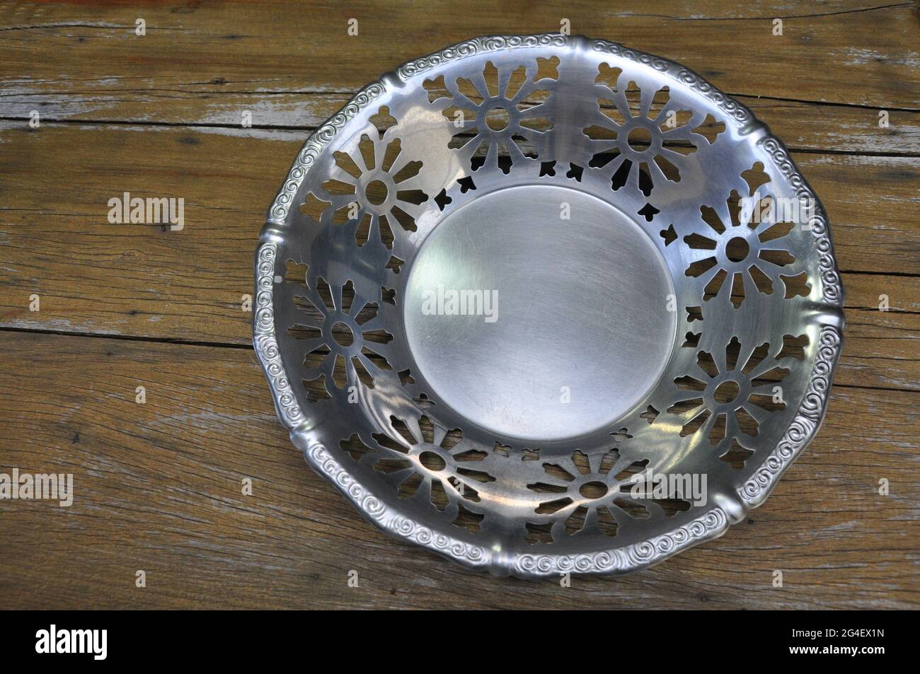 Tablett oder Obstschale oder Mittelstück aus antikem Aluminium in Edelstahl, alle Spitzen und geprägt, Vintage und Retro auf Holzhintergrund mit Kopierfläche Stockfoto