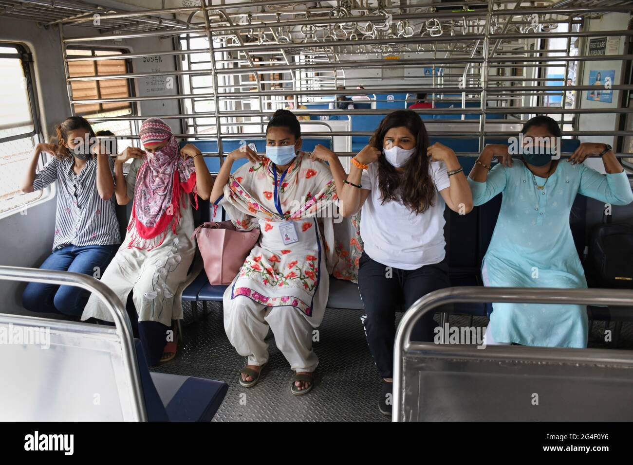 Mumbai, Indien. Juni 2021. Frauen tragen Gesichtsmasken als Vorsichtsmaßnahme gegen die Verbreitung von covid-19 führen Yoga-Übungen in einem lokalen Zug in Mumbai durch.der Internationale Yoga-Tag wird jährlich am 21. Juni auf der ganzen Welt gefeiert. (Foto von Ashish Vaishnav/SOPA Images/Sipa USA) Quelle: SIPA USA/Alamy Live News Stockfoto