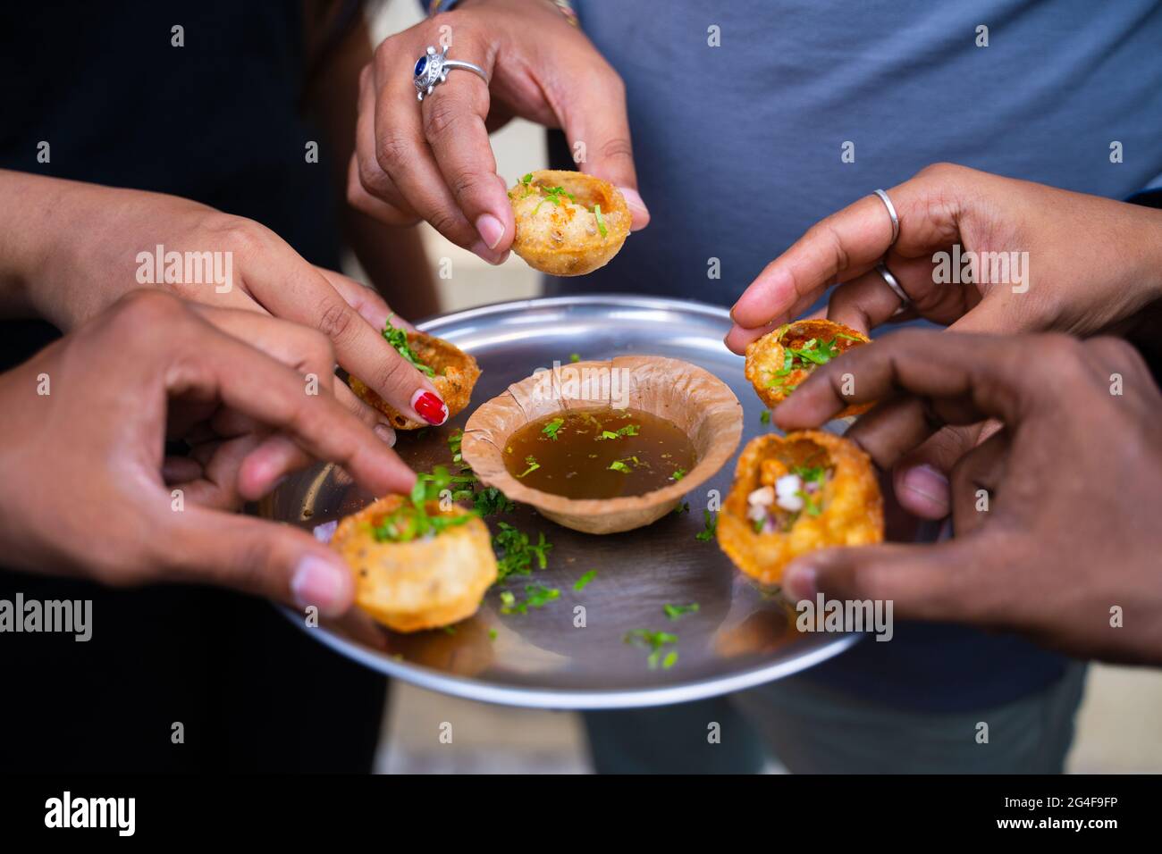 Nahaufnahme, Gruppe von Freunden Hände nehmen Pani puri Snacks vom Teller - Konzept des Sharing Food oder indische Abend Street Food. Stockfoto