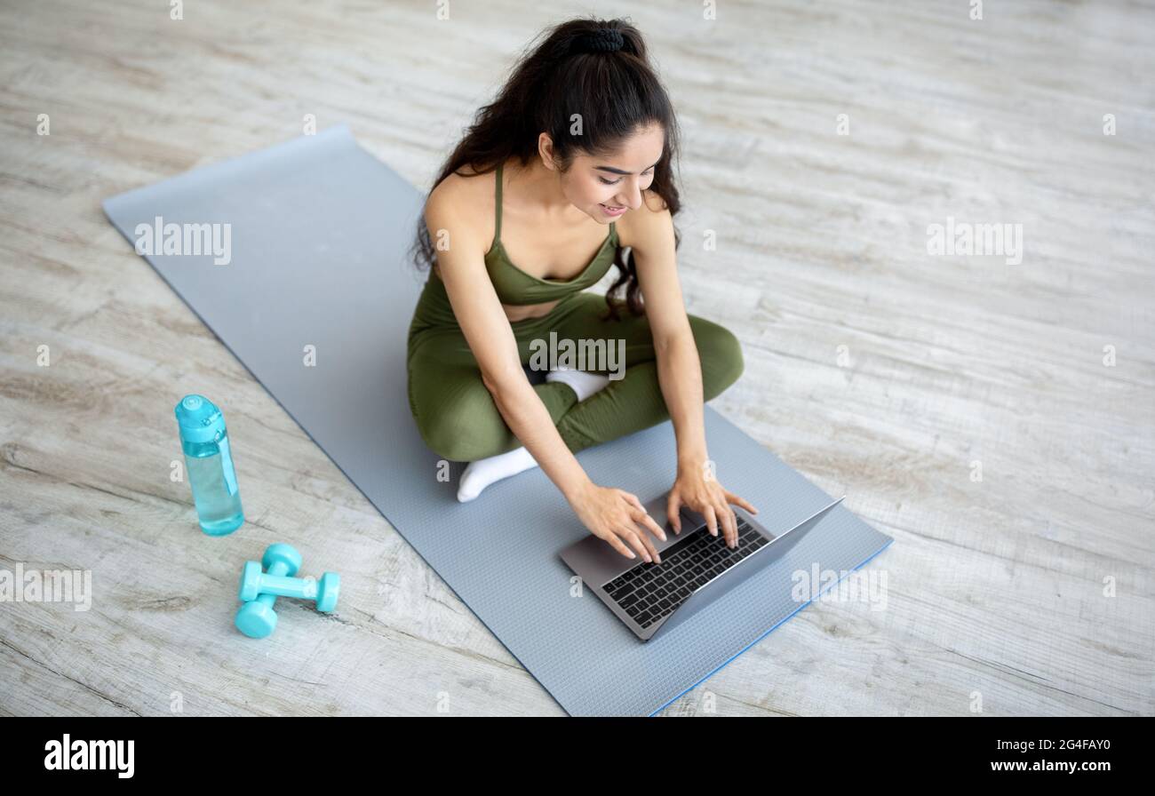 Millennial indische Frau, die vor dem inländischen Training Online-Sportvideos auf dem Laptop ansieht, oben. Aktiver Lebensstil Stockfoto