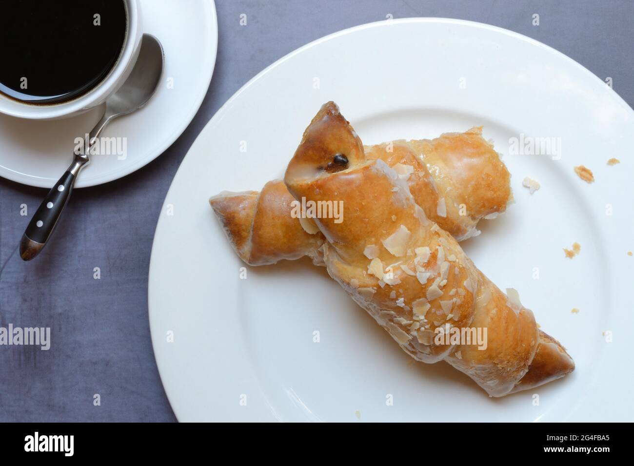 Mandelcroissant auf Teller mit Kaffeetasse, Deutschland Stockfoto