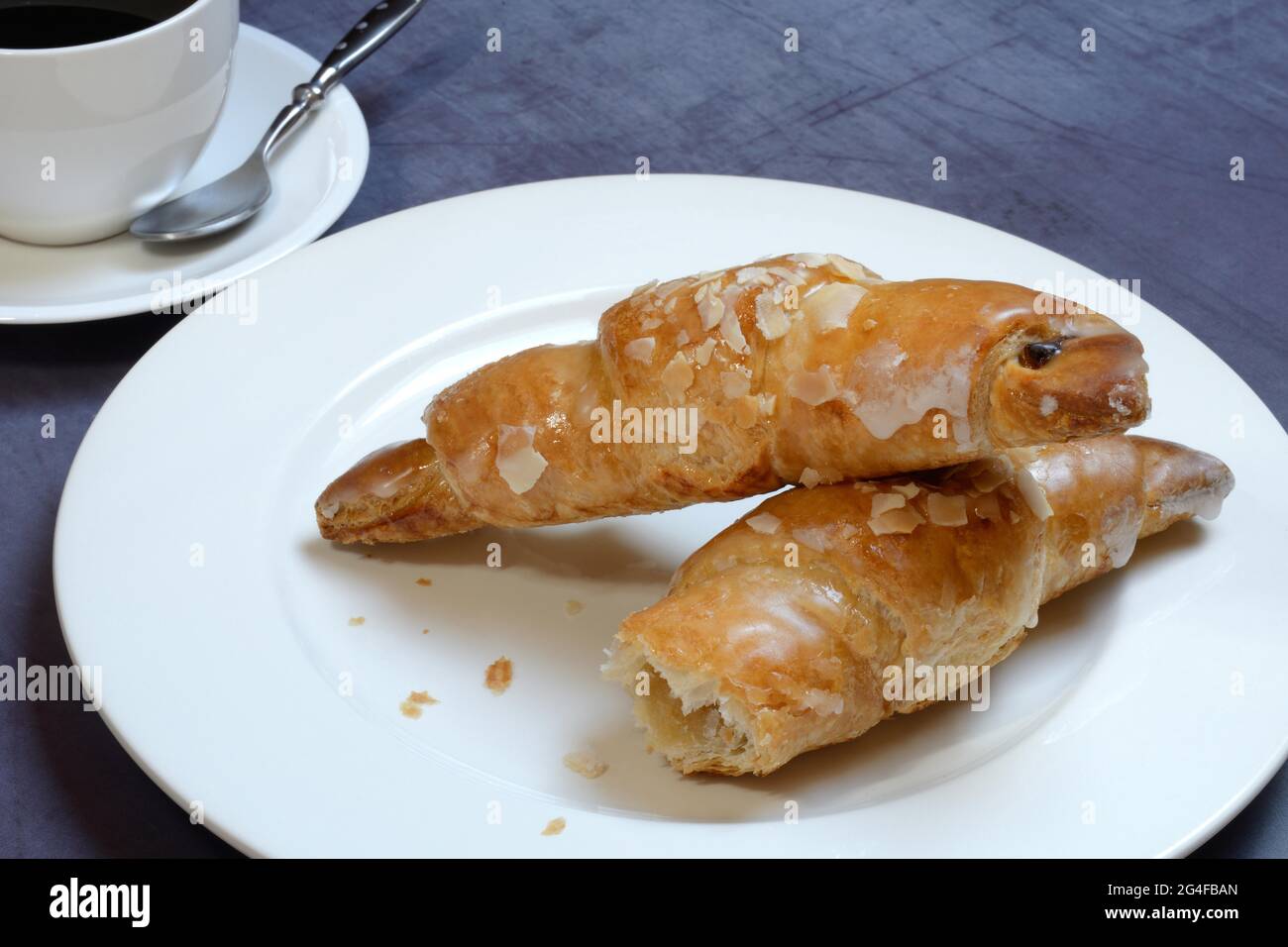 Mandelcroissant auf Teller mit Kaffeetasse, Deutschland Stockfoto